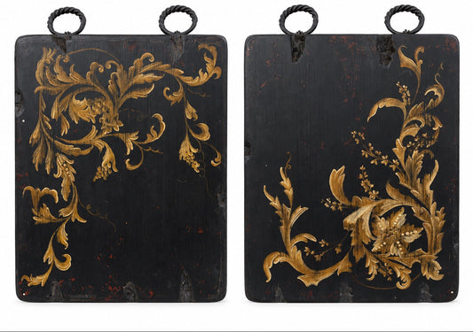 A pair of rectangular black hanging panels or boxes with ornate gold floral scrollwork and hanging loops at the top, shown against a plain white background.