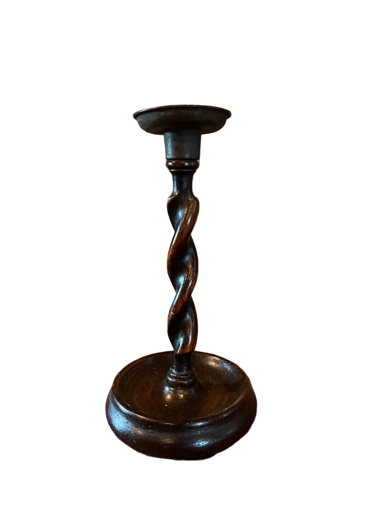 Wooden candlestick on a wooden table with decorative wall art in the background