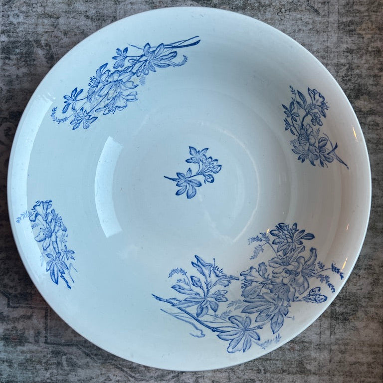 A white ceramic bowl with blue floral patterns, photographed from above on a textured gray surface.