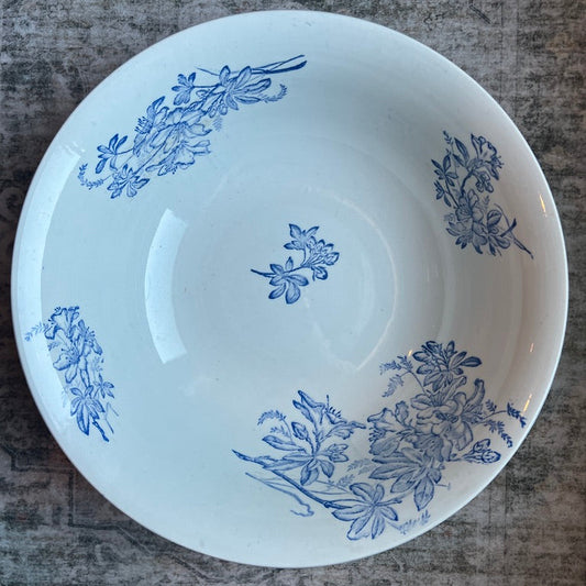 A white ceramic bowl with blue floral patterns, photographed from above on a textured gray surface.