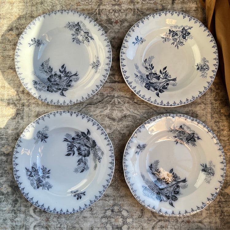 Four white plates with blue floral patterns on a textured surface